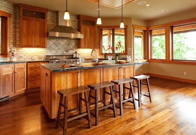 A Rustic Kitchen With A Large Island, Stainless Steel Appliances, And Newly Installed Hardwood Floors.