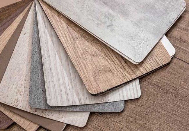 A Close-Up View Of A Fan Of Laminate Flooring Samples In Various Colors And Wood-Look Patterns.