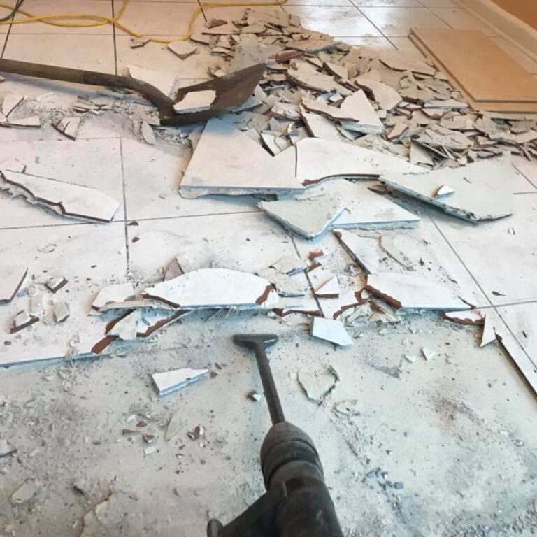 A Close-Up View Of A Floor Jackhammer Breaking Up And Removing Old White Tile Flooring.