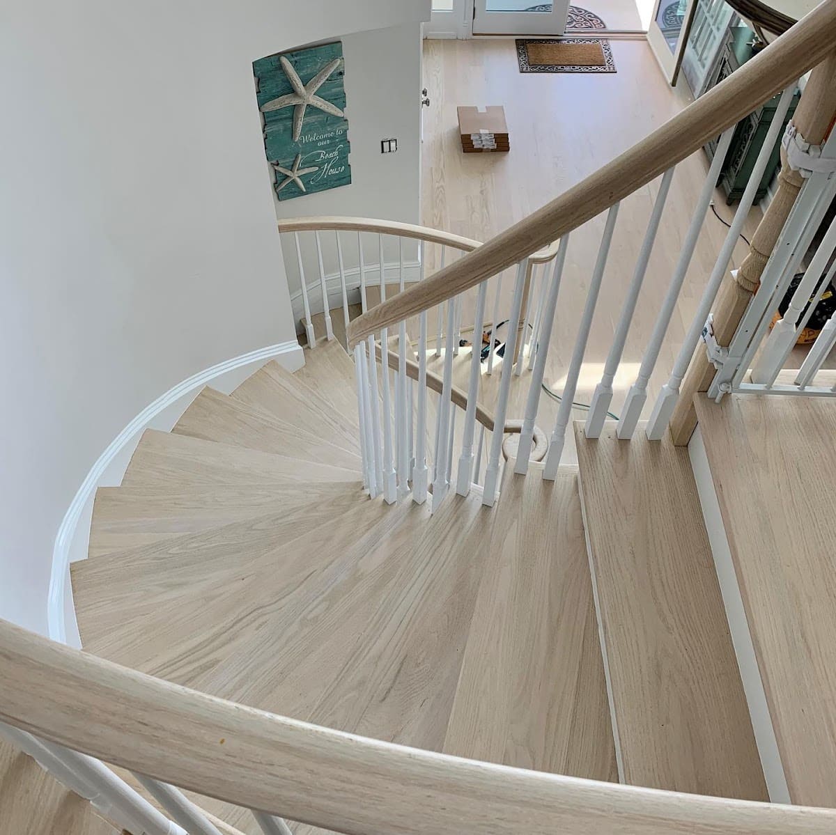 Curved White Oak Staircase With Matching Hardwood Flooring In Coastal Home