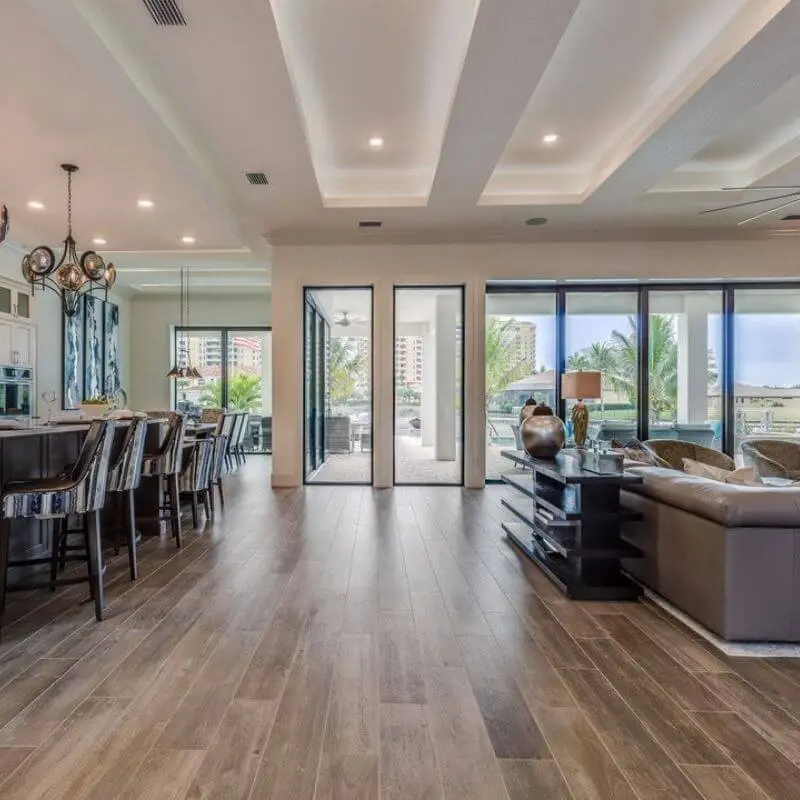 A Spacious Open-Concept Living Room And Kitchen With Light-Brown Wood-Look Tile Flooring.